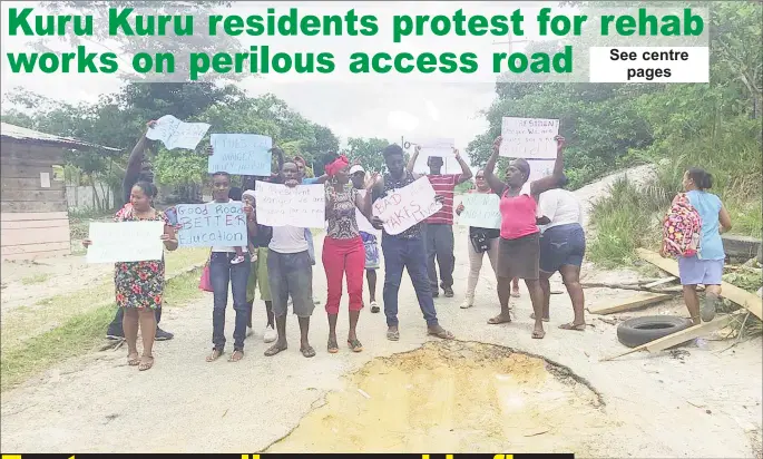  ??  ?? Parents and residents of Kuru Kuru, Soesdyke-Linden Highway, with their placards yesterday, standing in front of the first pothole at the start of the access road.