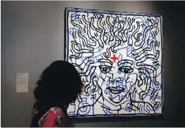  ?? AP ?? A woman looks at work by Keith Haring, called Untitled, on display at the Michael Jackson: On The Wall exhibition at the National Portrait Gallery in London.