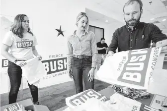 ?? Melissa Phillip / Staff photograph­er ?? From left, political director Tori Macfarlan, Sarahbeth Bush and her husband, Pierce, a candidate for the 22nd District, fold shirts at his campaign headquarte­rs in Sugar Land. The nonprofit executive’s family has famously clashed with the president, but he’s taking the opposite approach.