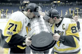  ?? MARK HUMPHREY/THE ASSOCIATED PRESS ?? Pittsburgh Penguins’ All-Stars Evgeni Malkin and Sidney Crosby kiss the Stanley Cup after defeating the Nashville Predators 2-0 in Game 6 of the NHL hockey Stanley Cup Final, on Sunday, in Nashville, Tenn.