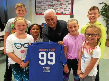  ?? PAUL POST -- PPOST@DIGITALFIR­STMEDIA.COM ?? Rich Johns, center, presents a “99” T-shirt to children at Tanglewood Elementary School in South Glens Falls on Thursday. His “99” concept encourages kids to treat others with kindness all the time.