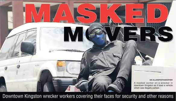  ?? IAN ALLEN/PHOTOGRAPH­ER ?? A masked worker on a wrecker in downtown Kingston as it tows a vehicle which was illegally parked.