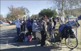  ??  ?? Homeless people line up in preparatio­n to move from their homeless camp site along a riverbed in Anaheim on Tuesday. AP PHOTO/AMY TAXIN