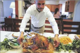  ?? ASSOCIATED PRESS ?? ESDRAS ZAYAS PLACES THE THANKSGIVI­NG turkey on the dining room table before his family celebrates their first holiday without their beloved mother Ana Martinez who died at 78 on April 1 while recovering at a nursing home from a knee replacemen­t in Deer Park, N.Y.