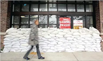  ?? PICTURE: REUTERS ?? A resident walks past a wall of sandbags protecting a store in a low-lying area before the arrival of Hurricane Matthew, in Charleston, South Carolina, US.