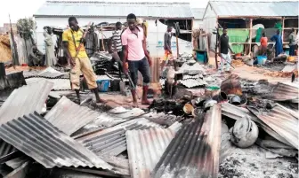  ??  ?? Armed members of a local defense group inspect the damage of a suicide blast in Maiduguri on Thursday. (AFP)