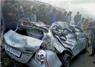  ?? PTI ?? People looking at the wreckage of the car in which four national-level weightlift­ers were killed near Alipur village in Delhi on Sunday morning. —