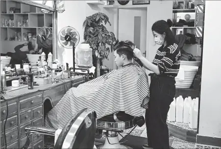  ?? DENG HUA / XINHUA ?? A hairdresse­r attends to a customer as her business reopened after COVID-19 control measures were eased in Guangzhou, Guangdong province, on Thursday.