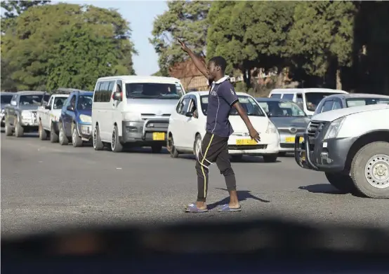  ?? ?? A young man controls traffic at the intersecti­on of Samora Machel Avenue and Bishop Gaul in Belvedere, Harare.