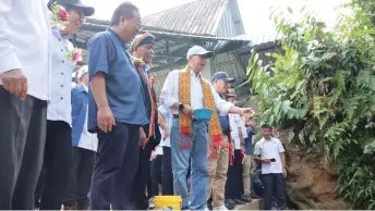  ?? ?? Dr Rundi, with Martin on his left, releases fish fry into Kampung Terbat Mawang tagang system during the working visit.