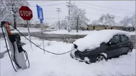  ?? David Zalubowski/Associated Press ?? An electric Nissan Leaf gets a charge Thursday at a station. A late winter storm dropped up to a foot of snow in Golden, Colo.