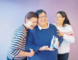  ?? MARLA BROSE/JOURNAL ?? Kathy Trujillo, center, is congratula­ted by sister Lydia Paiz, left, and niece Teri Salazar, right, after Trujillo received her Nambé angel for being one of two Angels Among Us recipients. Trujillo works with special needs adults, the homeless and...