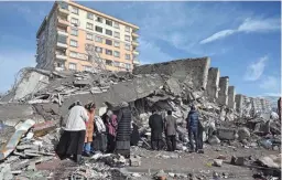  ?? OZAN KOSE/AFP VIA GETTY IMAGES ?? Families stand beside collapsed buildings in Kahramanma­ras, southeast Turkey, on Tuesday following Monday’s deadly earthquake.