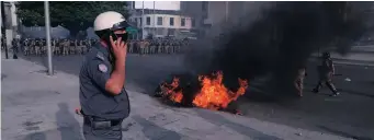  ??  ?? A LEBANESE policeman speaks on his cellphone next to a police motorcycle set on fire by anti-government protesters during protests against the government, in downtown Beirut, Lebanon, at the weekend.