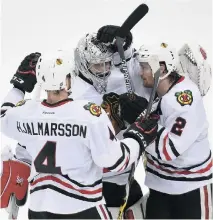  ?? HANNAH FOSLIEN/GETTY IMAGES ?? Teammates surround Chicago goalie Corey Crawford who has stopped 90 of 94 Minnesota shots in this series.