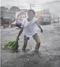  ?? EPA; Getty ?? Top, residents of Legazpi in Abay in the Philippine­s salvage what they can yesterday in the aftermath of Typhoon Kammuri; above, a resident battles high winds and flooding in Lipa town, Batangas province, before the storm made landfall