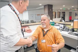  ?? AP PHOTO ?? Robert Tierney Jr., right, a patient registrati­on specialist at Mercy Medical Center, who lost his home in the recent fires, receives a message from Dignity Health North State’s spokesman Mike Mangas, left, that a citizen wants to offer him a place to...