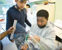  ?? STEPHEN M. KATZ/STAFF ?? Erion Johnson, right, and Jeremiah Blount cut plastic wrap to add to their solar oven, a STEM project for sixth graders at Horizons Hampton Roads summer camp hosted by Chesapeake Bay Academy in July.