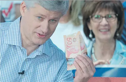  ?? JONATHAN HAYWARD/THE CANADIAN PRESS ?? Conservati­ve Leader Stephen Harper holds up money as an illustrati­on of the Liberals’ proposed tax hikes in Trois-Rivières on Thursday. Harper took the opportunit­y to link the firing of the Liberal party’s campaign co-chair to the sponsorshi­p scandal.