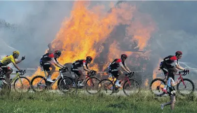  ?? PHOTO: REUTERS ?? Literally on fire . . . The Tour de France peloton passes burning hay bales during stage six from Brest to MurdeBreta­gne, yesterday.