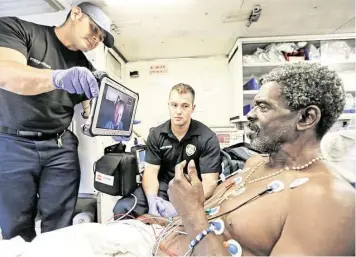  ?? Melissa Phillip / Houston Chronicle ?? Firefighte­r paramedics Raul Zamarripa, left, and Alden Speer, center, work with Dr. Kenneth Totz, shown on tablet screen, to assist patient Johnny Bruins last month as part of the ETHAN program.