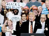  ?? RICK SCUTERI/AP ?? “Michael the Black Man,” a radical fringe activist from Miami, is seen behind President Donald Trump in Arizona.