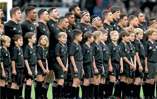  ?? PHOTO: PHOTOSPORT ?? The All Blacks, and young friends, stand for the national anthems before the match against the Barbarians last weekend. The playing squad numbers 43, not counting a large supporting cast.