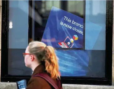  ?? — Reuters ?? E-banking era: A woman walking past a poster informing customers that a branch of Nat West Bank is now closed, in Hale, England. RBS is encouragin­g customers to use online and mobile services.