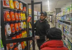  ?? BEBETO MATTHEWS — THE ASSOCIATED PRESS ?? Leo Pichardo, left, a store associate at Gristedes supermarke­t, retrieves a container of Tide laundry soap from a locked cabinet Jan. 31at the store in New York.