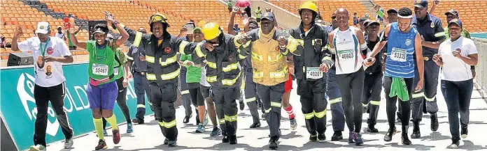 ??  ?? Firefighte­rs Nkosi Mzolo, Nhlakaniph­o Khoza and Siphiwe Tshabalala are joined by other runners to celebrate completing the race at the FNB Stadium in Soweto.