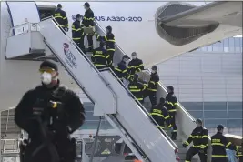  ?? MICHAL KAMARYT — CTK ?? A police officer holds a gun as firefighte­rs unload an airplane after its arrival at the Vaclav Havel Airport in Prague, Friday. The airplane brought medical aid and protective materials against coronaviru­s from China.