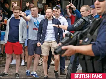  ??  ?? Target: The British fans react to the chanting Russians as heavily-armed police look on BRITISH FANS