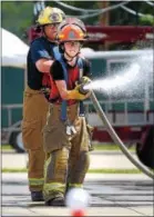  ?? PETE BANNAN — DIGITAL FIRST MEDIA ?? Charles Ziegler of Wagontown Fire Company and Alexandra DiPaolo of the Glen Moore Fire Company advance a hose as part of Chester County Department of Emergency Services’ Junior Public Safety Camp Olympics Thursday. The test was to knock a ball, in the...