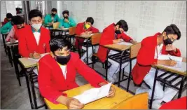  ??  ?? Students wear masks while giving their examinatio­n, to prevent coronaviru­s, at a school in Moradabad