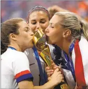  ?? Maja Hitij Getty Images ?? KYLIAN MBAPPE, left, of France kisses the World Cup trophy in Moscow in July 2018. Kelley O’Hara, Alex Morgan and Allie Long smooch their trophy after capturing the women’s title last weekend in Lyon, France.