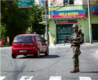  ?? Ricardo Borges/Folhapress ?? Militar usa corda ligada a malha com pregos para furar pneu de carro que furar bloqueio