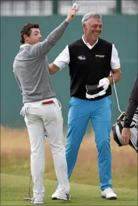  ?? AP PHOTO ?? RORY MCILROY, left, of Northern Ireland, holds up a 20 pound note as Darren Clarke, of Northern Ireland, smiles after winning a wager on the 18th green by holing a putt during a practice round for the British Open Golf championsh­ip at the Royal...