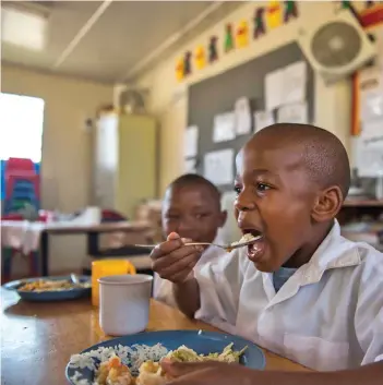  ?? /Gallo Images ?? Philang Special School children enjoy their meal during the ‘Chefs who Share – the ART of Giving’ veggie box cook-off in Kwa-thema.