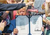  ?? AP PHOTO/ALEX BRANDON ?? President Donald Trump holds up H.R. 1327, an act ensuring that a victims’ compensati­on fund related to the Sept. 11 attacks never runs out of money.