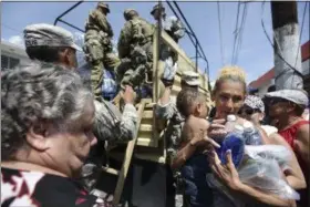  ?? CARLOS GIUSTI — THE ASSOCIATED PRESS ?? National Guard Soldiers arrive at Barrio Obrero in Santurce to distribute water and food among those affected by the passage of Hurricane Maria, in San Juan, Puerto Rico, on Sunday. Federal aid is racing to stem a growing humanitari­an crisis in towns...