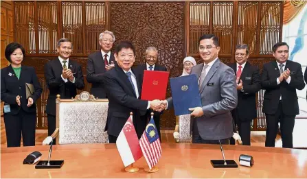  ?? — Bernama ?? Sealing the deal: Azmin (third from right) and Khaw exchanging the HSR Bilateral Agreement at Perdana Putra in Putrajaya. Looking on are Dr Mahathir and (from right) Transport Minister Anthony Loke Siew Fook, Foreign Affairs Minister Datuk Saifuddin Abdullah, Deputy Prime Minister Datuk Seri Dr Wan Azizah Wan Ismail and Teo.