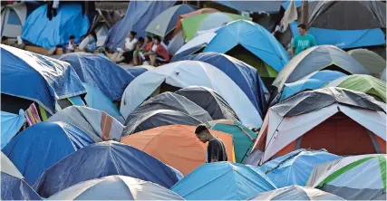  ??  ?? Migrante caminando por un campamento de refugiados en Matamoros, México