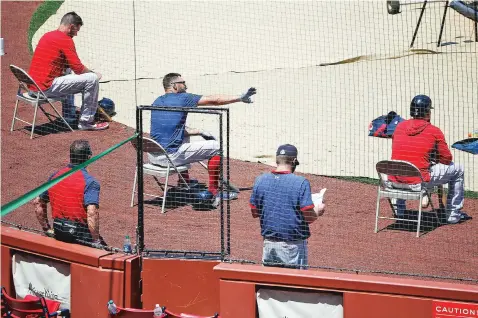  ?? ASSOCIATED PRESS FILE PHOTO ?? Red Sox players sit apart for social distancing during practice July 5 at Fenway Park in Boston. Public health experts have mixed feelings about baseball’s hopes to open its season Thursday. There is optimism because of the nature of the sport itself, which produces less on-field risk than basketball, football or hockey. Then again, players and their families face a daunting task staying safe away from the ballpark, especially with teams traveling to and from hard-hit regions, including Florida and Texas.