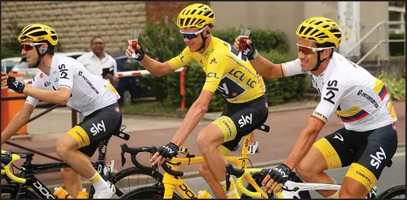  ??  ?? Chris Froome of Great Britain and Team Sky, donning the yellow jersey, grabs a glass of champagne during the 21st and final stage of the Tour de France in Paris yesterday.