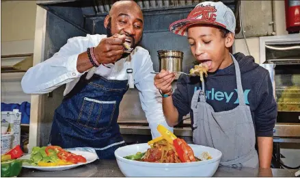  ?? CHRIS HUNT PHOTOGRAPH­Y CONTRIBUTE­D BY ?? Chef Cheikh Ndiaye teaches 12-year-old Fallou Diouf (who is half Senegalese) to cook some of the national dishes of his father’s homeland in the kitchen of Project Community Connection­s Inc. in Atlanta recently. Here, they are taking a first bite of the Chicken Yassa.