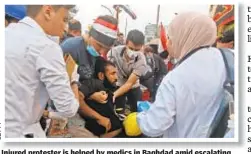  ??  ?? Injured protester is helped by medics in Baghdad amid escalating violence during anti-government rallies throughout Iraq on Tuesday.