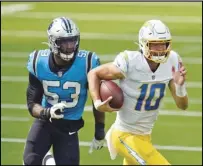  ?? Associated Press ?? RUN FOR IT Chargers quarterbac­k Justin Herbert (10) is chased by Carolina Panthers defensive end Brian Burns (53) during the first half on Sunday in Inglewood. The Panthers won 21-16.