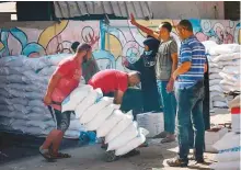  ?? AFP ?? A volunteer pushes a trolley of food rations outside an aid distributi­on centre run UNRWA at the Al Shati camp for Palestinia­n refugees in Gaza City yesterday.