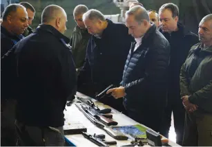  ?? (Baz Ratner/Reuters) ?? PRIME MINISTER Benjamin Netanyahu inspects a confiscate­d weapon yesterday at an army base in Beit El as Defense Minister Avigdor Liberman (left) looks on.