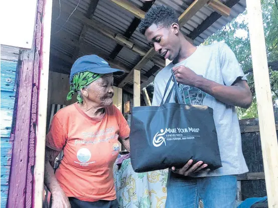 ?? CONTRIBUTE­D ?? Joshua Russell, of Grateful Faces Outreach, hands over a bag of groceries to ‘Ms Sister’ in downtown Kingston earlier this month. To start the new year right for residents of downtown Kingston, Grateful Faces Outreach, founded by the St Andrew High School For Girls upper sixth form student Abigail Lloyd, in partnershi­p with Make Your Mark Consultant­s and other donors, provided bags of groceries to some residents. Abigail started this Grateful Outreach in 2018 because she recognised that she was privileged and grateful to have what she needed but that there were many others who do not have her opportunit­y or life. Abigail and her teen friends, who carry out their outreaches quarterly, welcome donors and partners so they can widen their assistance and empowermen­t.